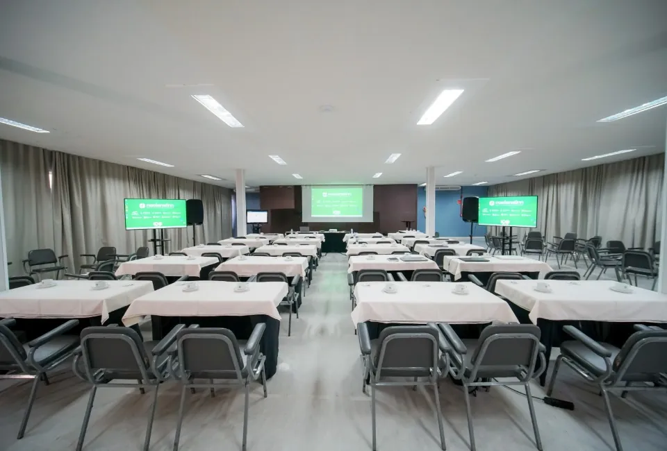 Sala de eventos com mesas e telões para convenção